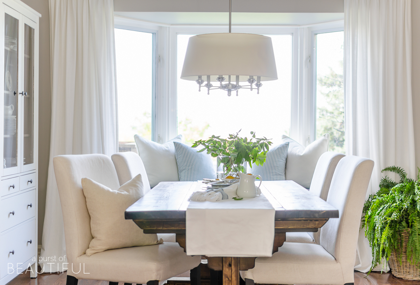 A DIY farmhouse dining table and window bench take center stage in this modern farmhouse dining room.