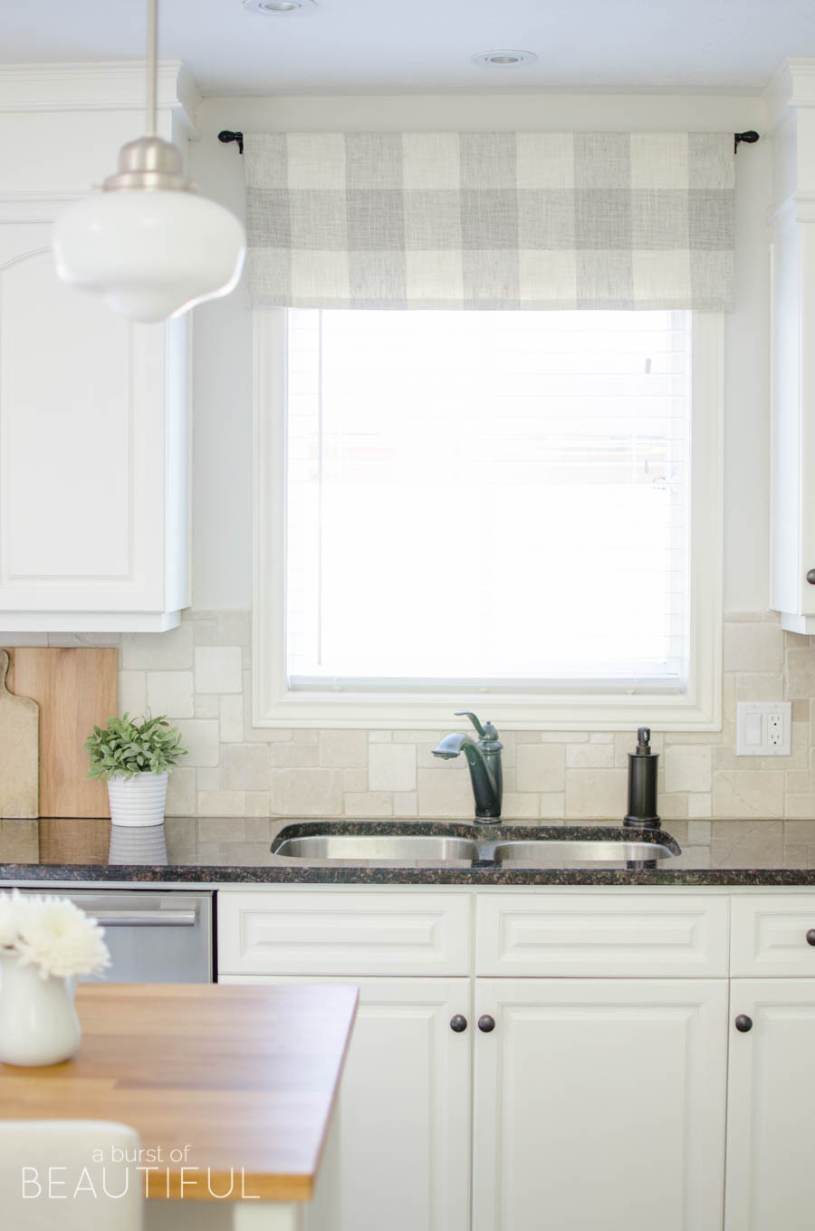 This simple farmhouse kitchen is the heart of this busy family's home. White cabinets, black granite counters and natural wood elements add plenty of texture and charm to this bright and airy space. 