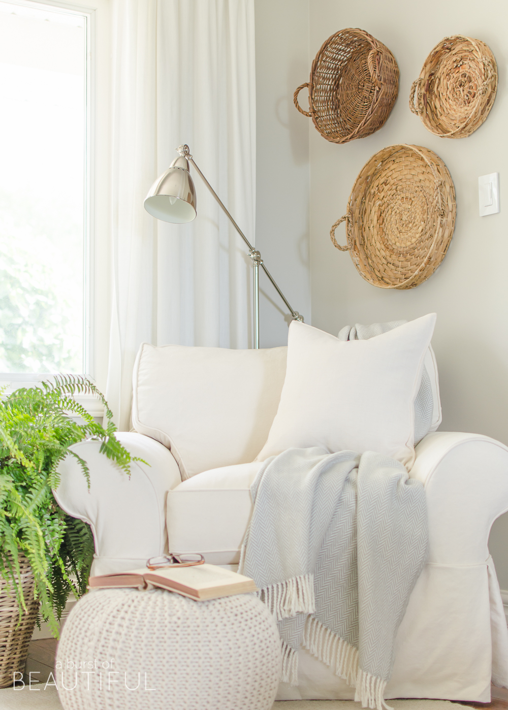 A white slipcovered sofa, layered gallery wall and natural wood elements help this charming farmhouse living room feel cozy and inviting. 