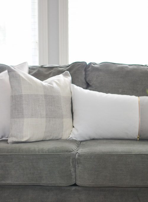 An assortment of grey and white pillows create a soft and inviting atmosphere in this modern farmhouse living room | A Burst of Beautiful