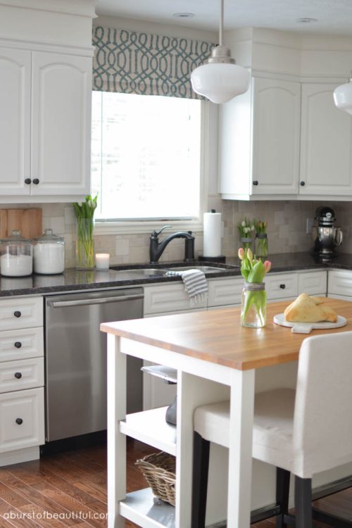 Beautiful white farmhouse kitchen, complete with butch block island, custom cabinetry and schoolhouse pendant lights | A Burst of Beautiful
