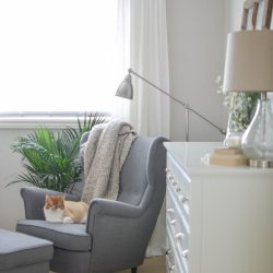 A neutral farmhouse bedroom welcomes spring with classic white bedding, a grey wingback chair and subtle pops of color | A Burst of Beautiful