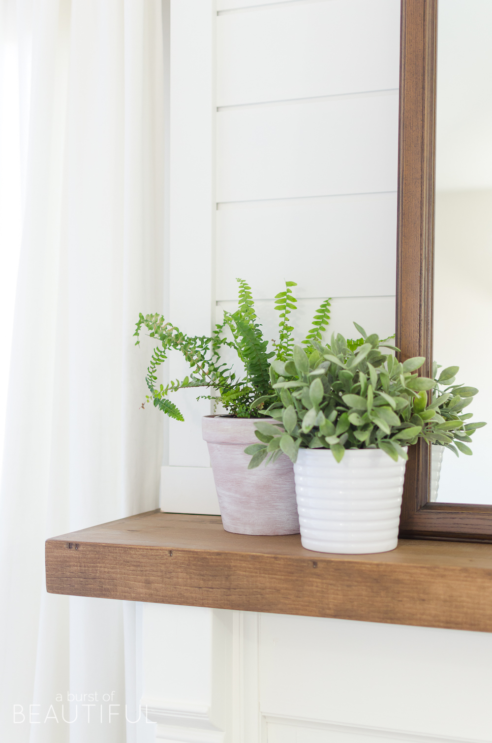 This cozy farmhouse master bedroom features a beautiful DIY shiplap fireplace, indigo ticking strip bedding and woven wood shades.