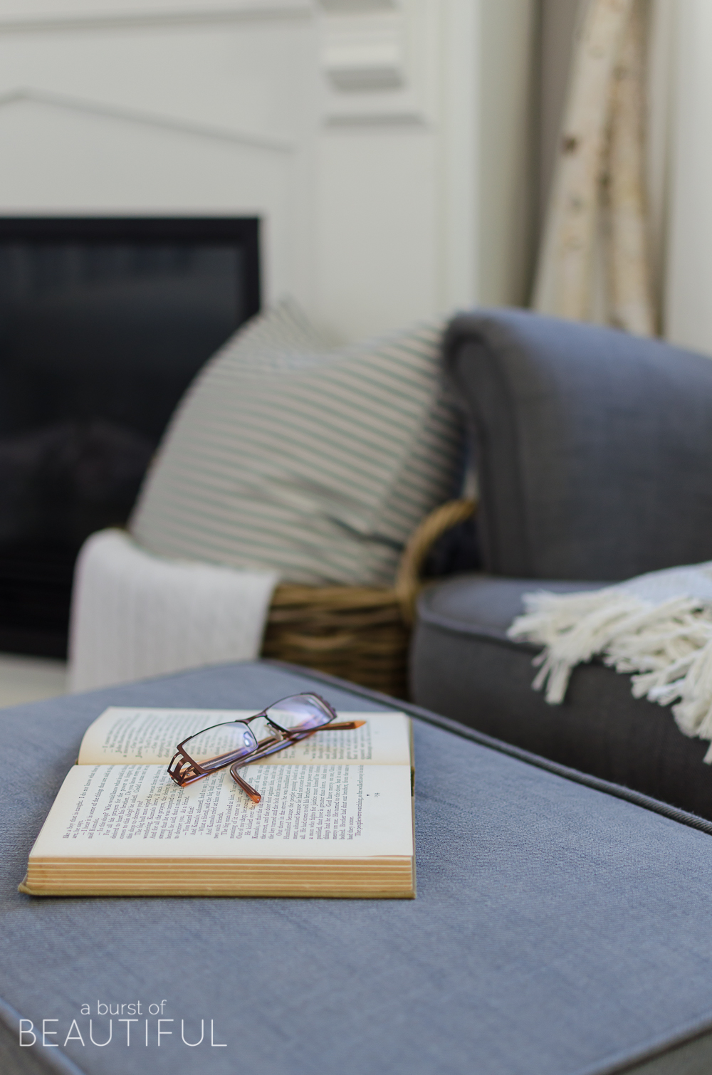 This cozy farmhouse master bedroom features a beautiful DIY shiplap fireplace, indigo ticking strip bedding and woven wood shades.
