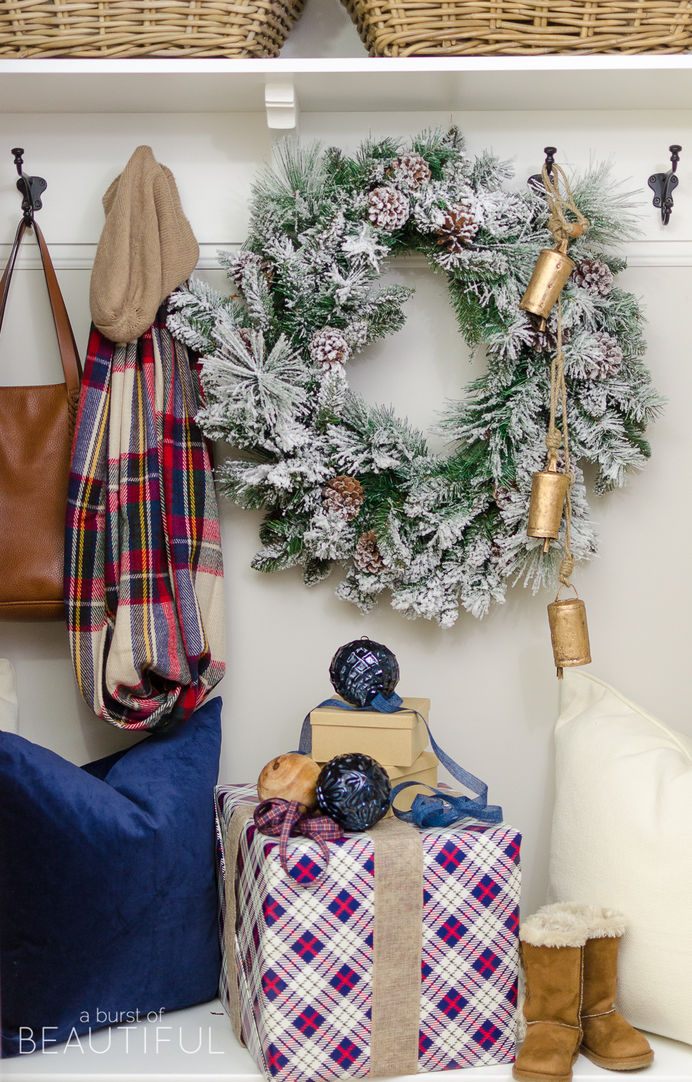 A simple Christmas entryway receives a dose of holiday charm with a flocked wreath, velvet pillows and packages wrapped in festive Christmas paper. 