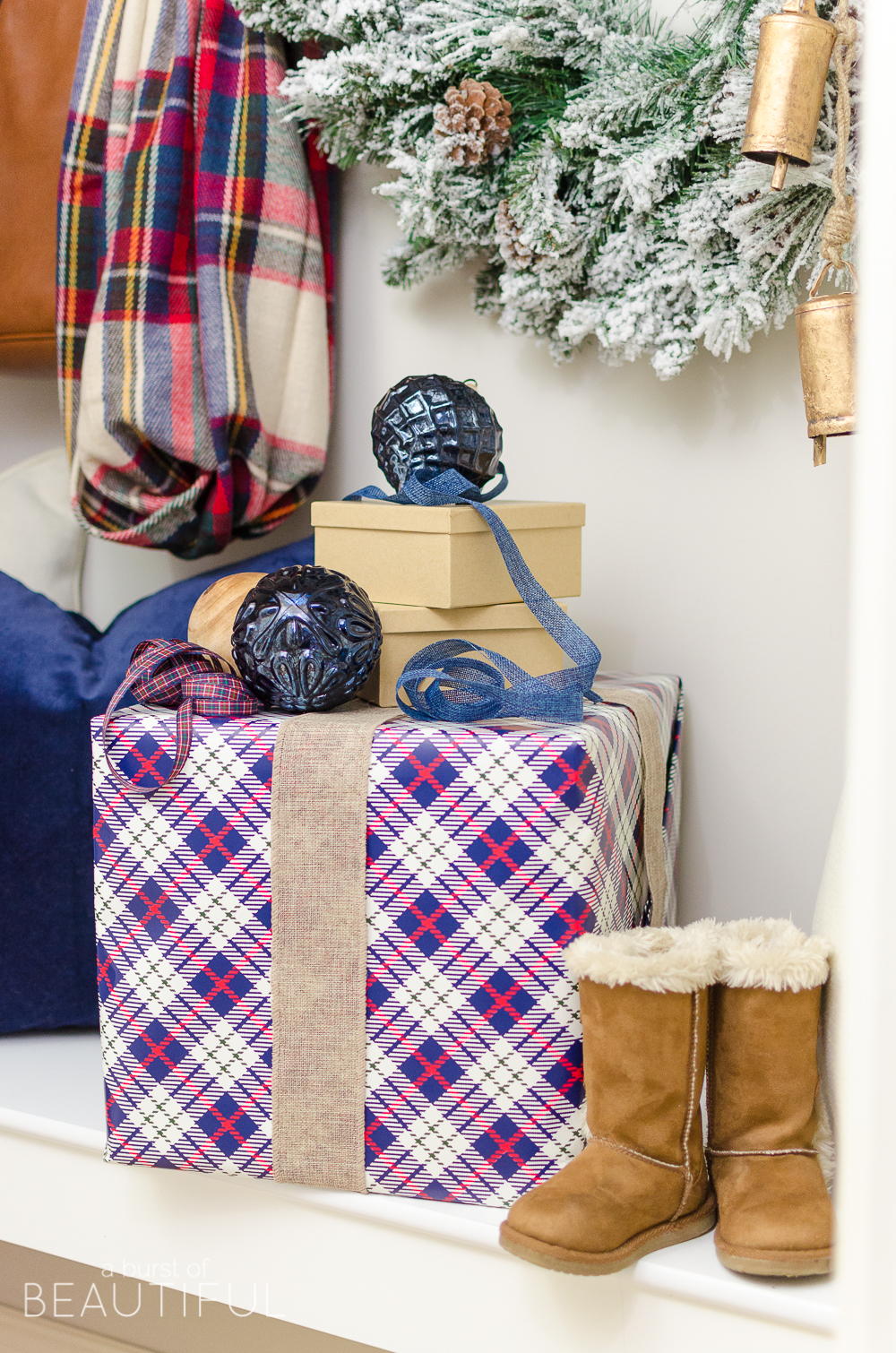 A simple Christmas entryway receives a dose of holiday charm with a flocked wreath, velvet pillows and packages wrapped in festive Christmas paper. 