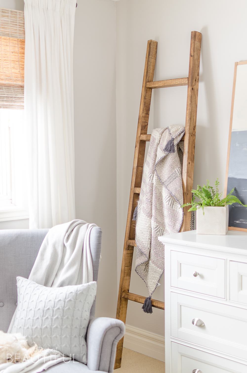 A simple DIY angled blanket ladder adds a touch of farmhouse charm to this cozy bedroom. 