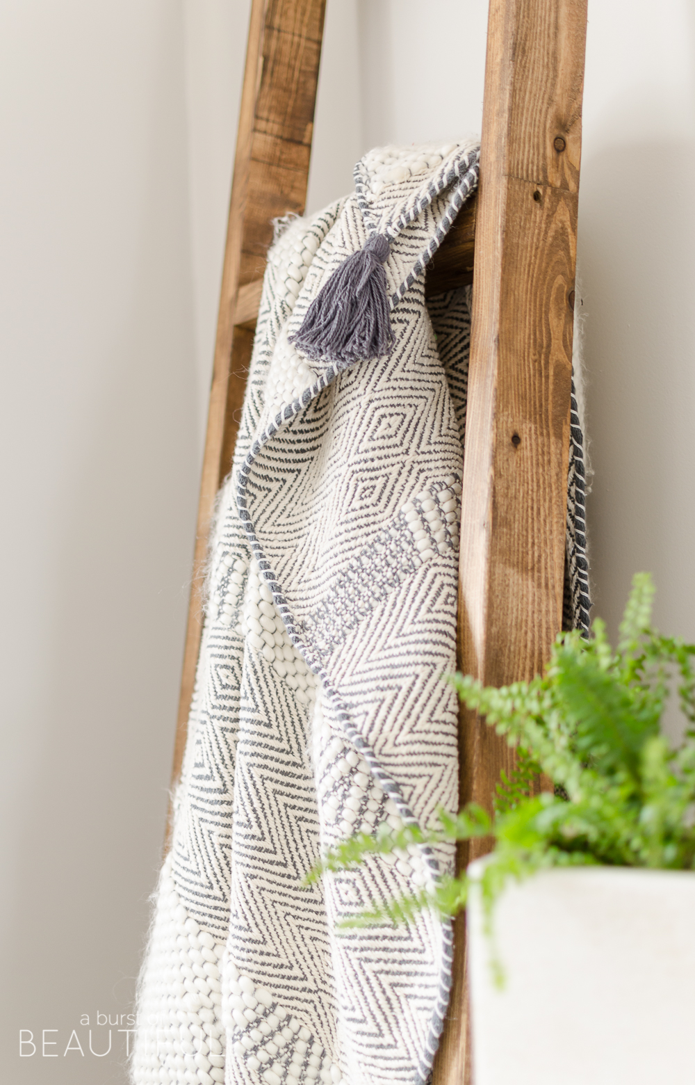 A simple DIY angled blanket ladder adds a touch of farmhouse charm to this cozy bedroom. 