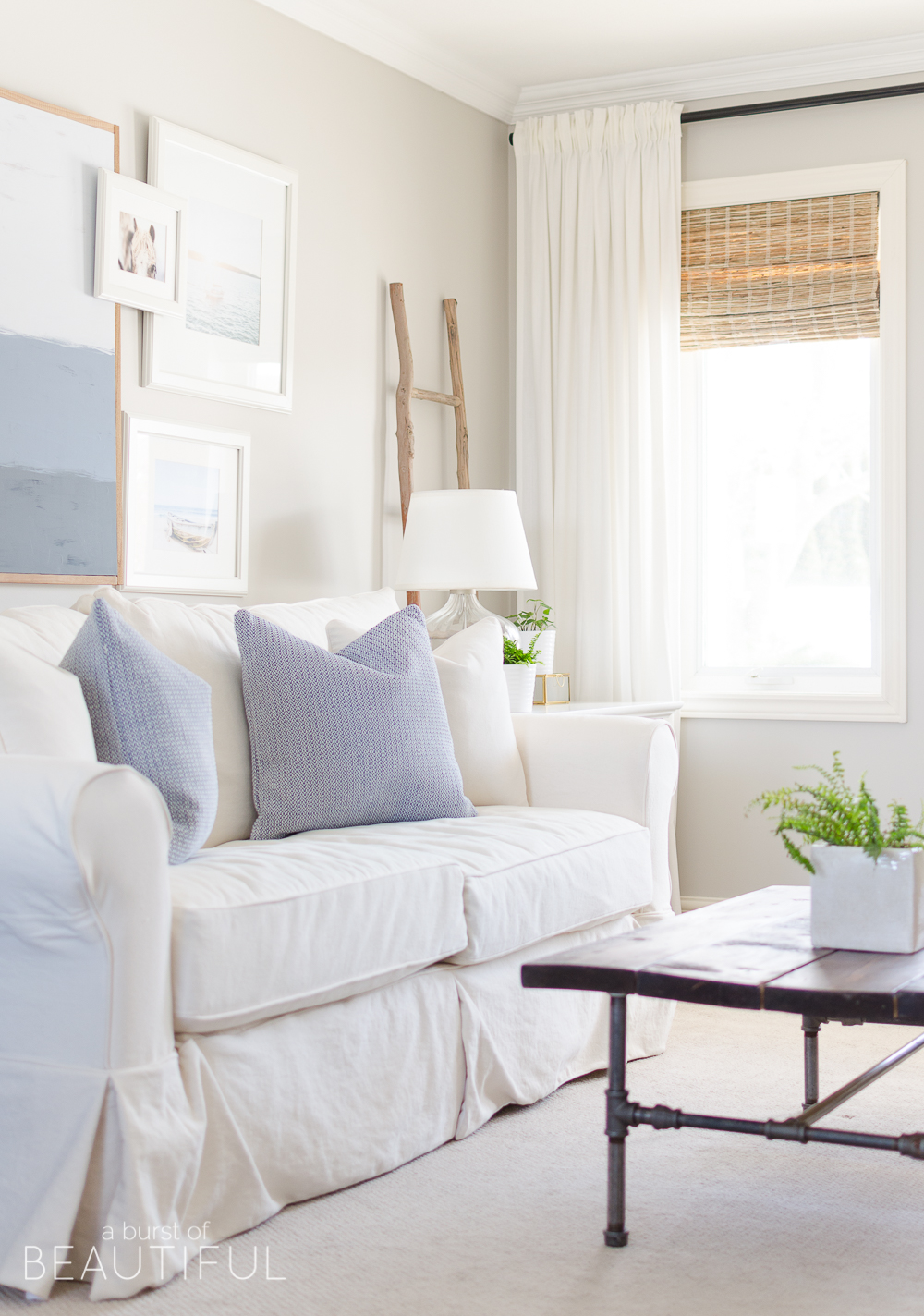Spring Home Tour | Our Living Room - A modern farmhouse living room looks fresh and cheerful for spring with a subtle blue and white color palette and layered coastal gallery wall. 