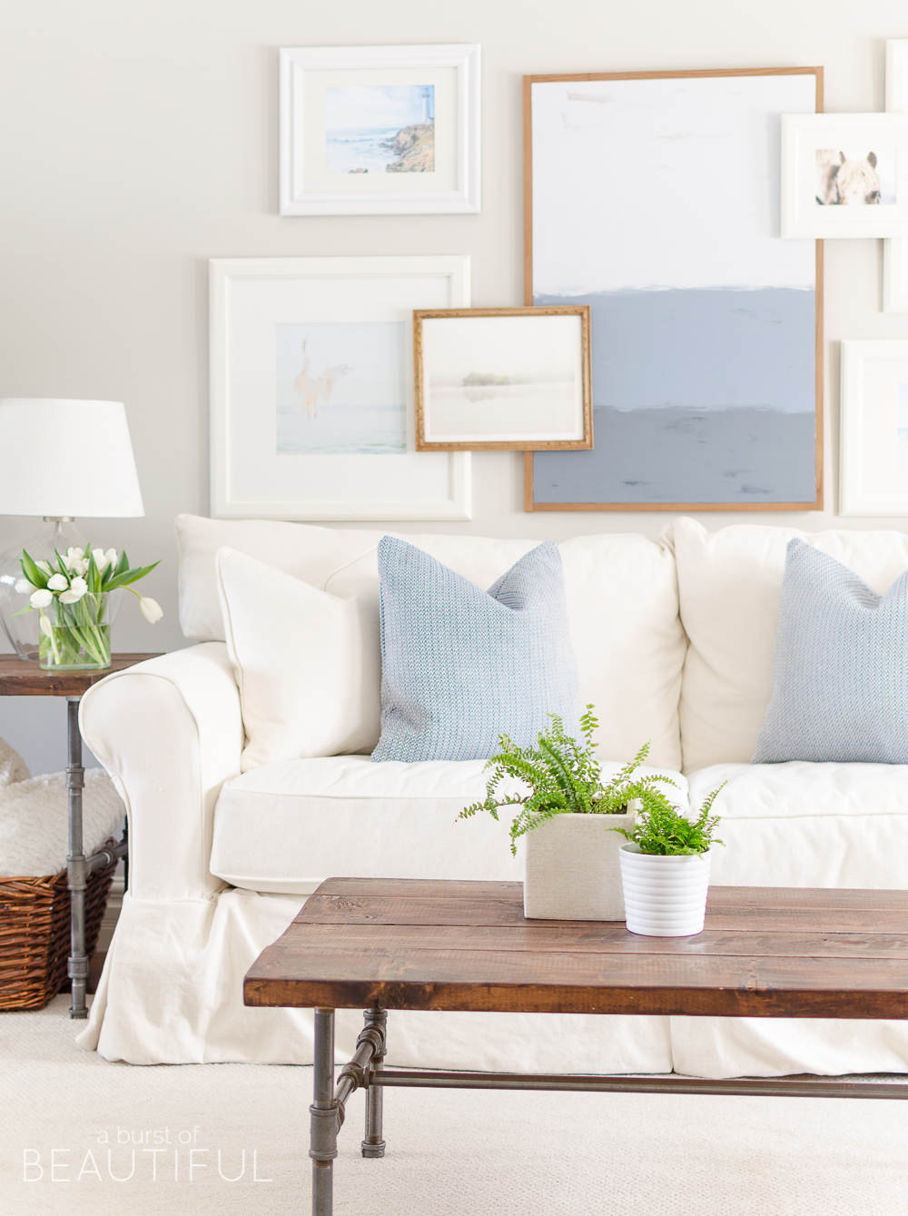 Spring Home Tour | Our Living Room - A modern farmhouse living room looks fresh and cheerful for spring with a subtle blue and white color palette and layered coastal gallery wall. 