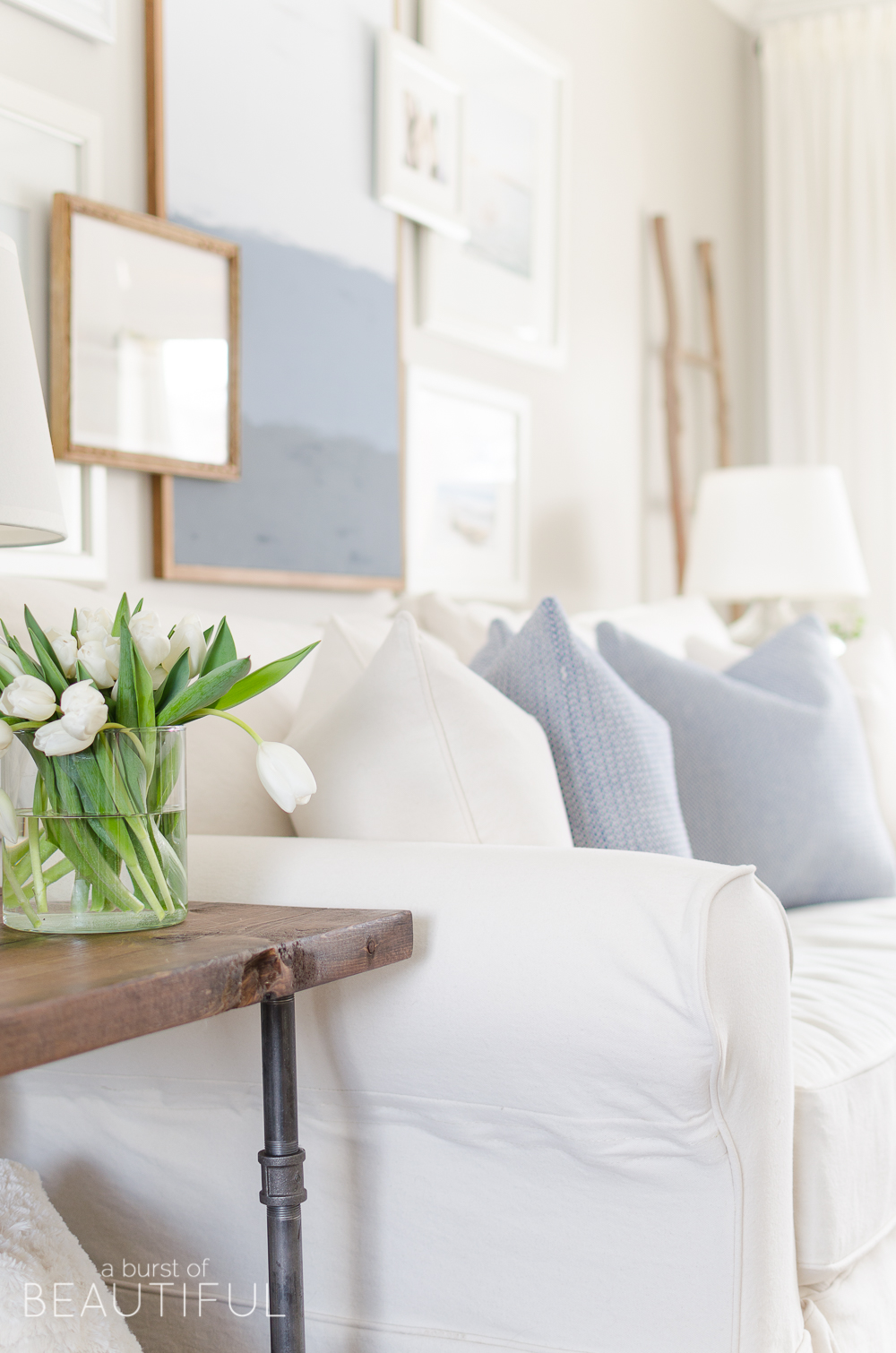 Spring Home Tour | Our Living Room - A modern farmhouse living room looks fresh and cheerful for spring with a subtle blue and white color palette and layered coastal gallery wall. 