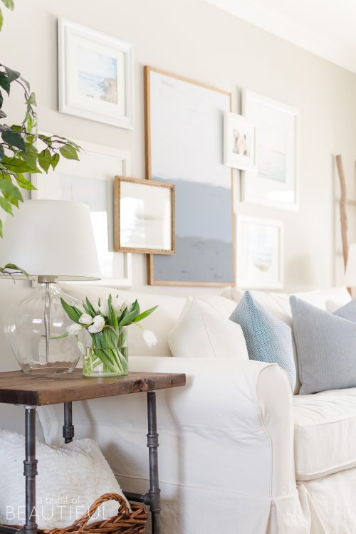 Spring Home Tour | Our Living Room - A modern farmhouse living room looks fresh and cheerful for spring with a subtle blue and white color palette and layered coastal gallery wall.