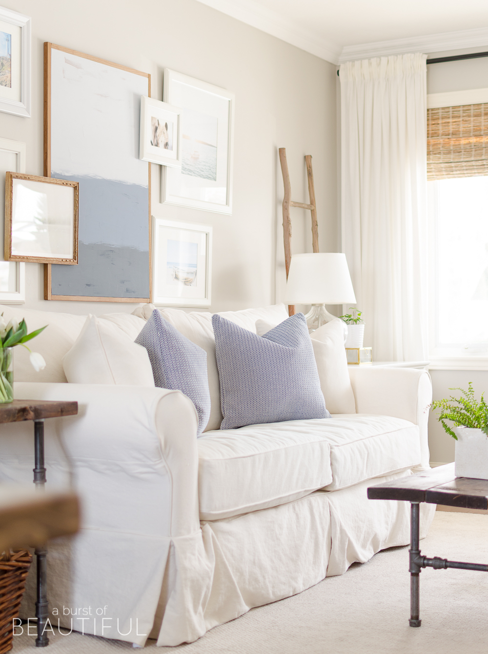 Spring Home Tour | Our Living Room - A modern farmhouse living room looks fresh and cheerful for spring with a subtle blue and white color palette and layered coastal gallery wall. 