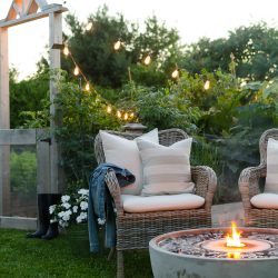 Create a cozy outdoor living space with ambiance using a fire fountain and Edison string lights.