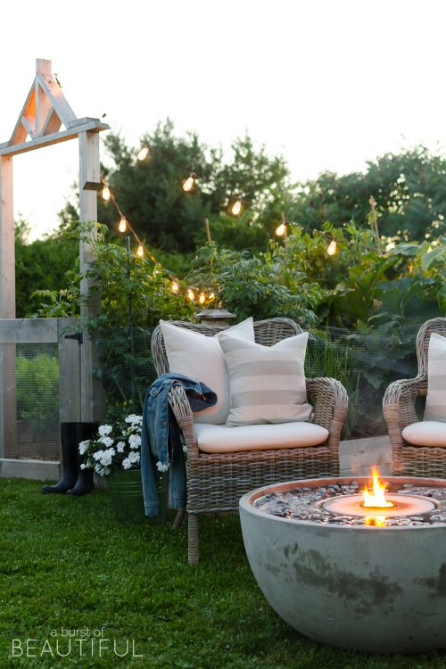 Create a cozy outdoor living space with ambiance using a fire fountain and Edison string lights.
