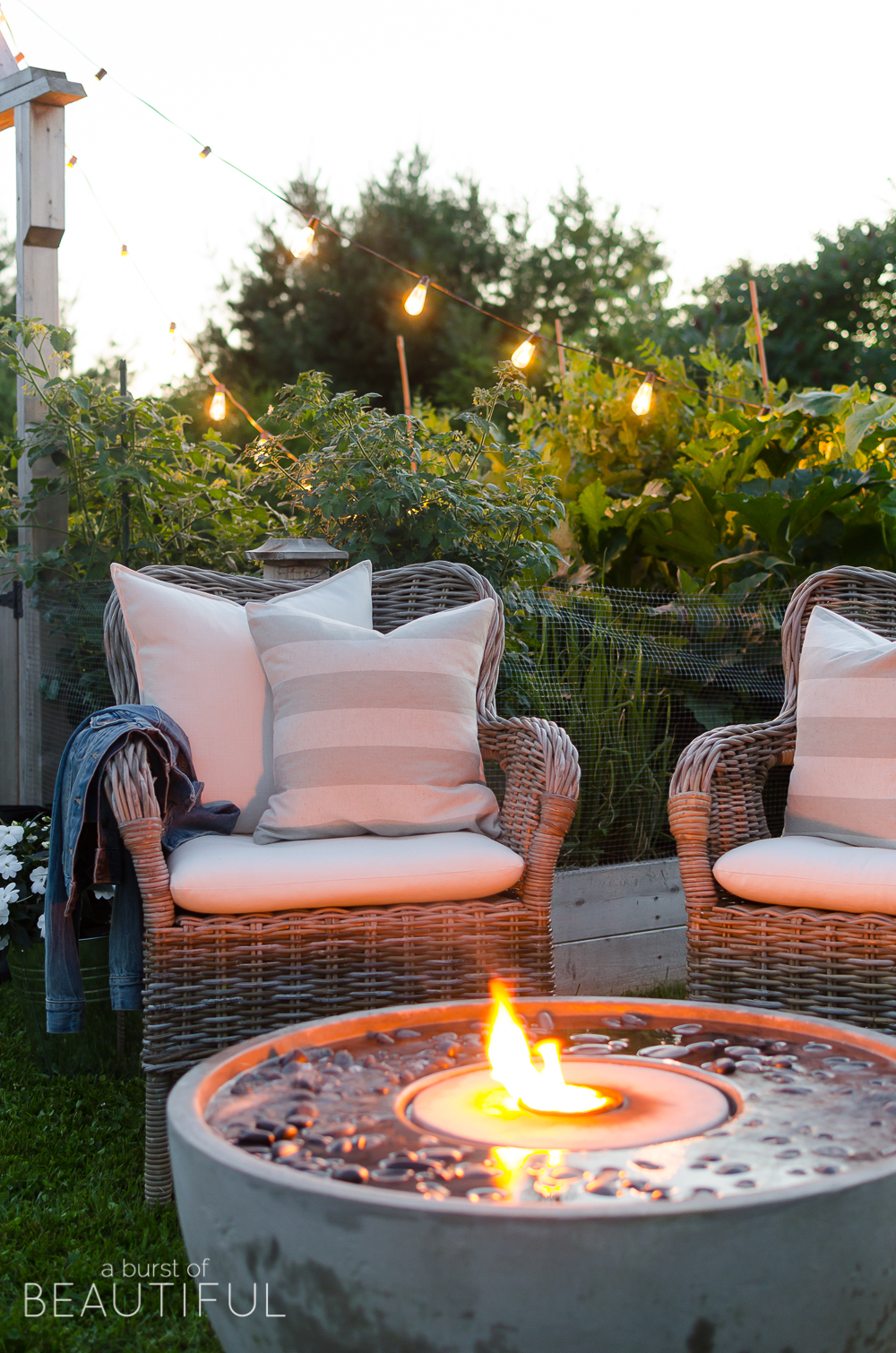 Create a cozy outdoor living space with ambiance using a fire fountain and Edison string lights.