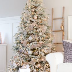 A snowy flocked Christmas tree decorated in silver and rose gold adds a big dose of holiday cheer to this modern farmhouse living room