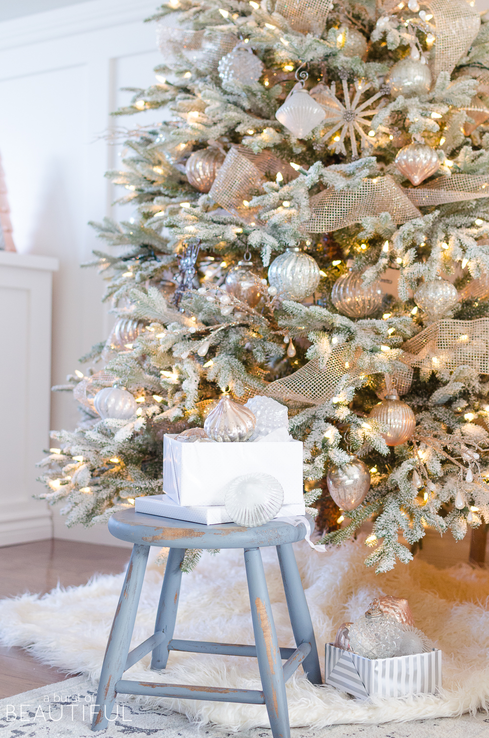 A snowy flocked Christmas tree decorated in silver and rose gold adds a big dose of holiday cheer to this modern farmhouse living room
