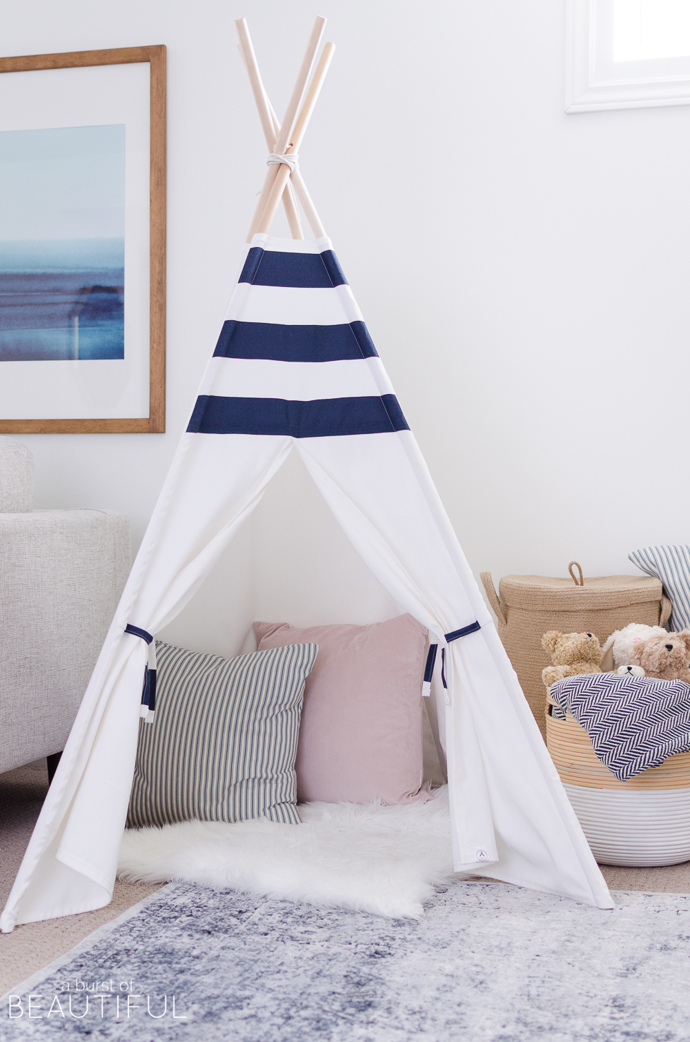 Hints of blue pop against bright white walls in this cheerful playroom, featuring a kid's desk, teepee and whimsical art.