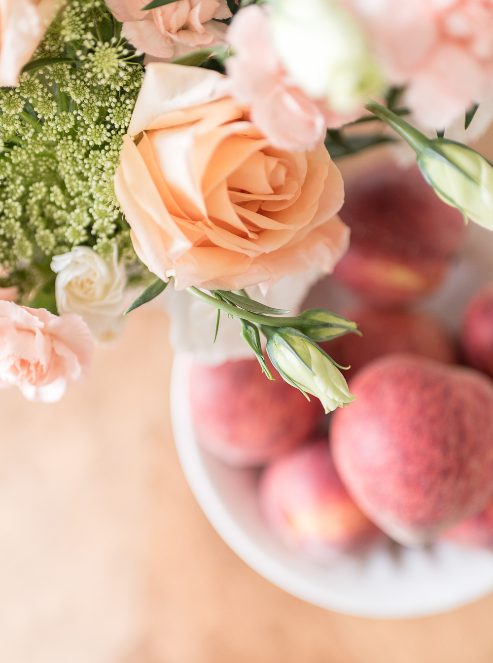 Fresh flowers in soft peach, blush and cream hues paired with a bowl of juicy peaches make an effortless centerpiece for a simple summer gathering.