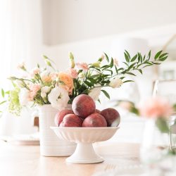 Fresh flowers in soft peach, blush and cream hues paired with a bowl of juicy peaches make an effortless centerpiece for a simple summer gathering.